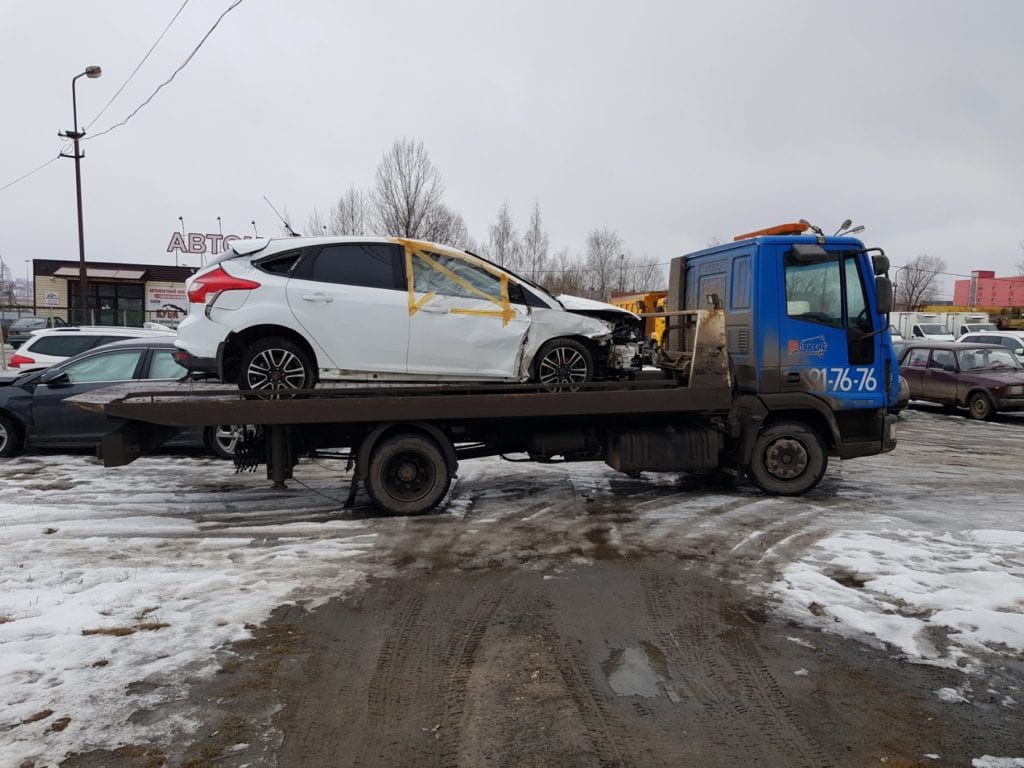 Белый автомобиль Ford Focus после аварии на эвакуаторе